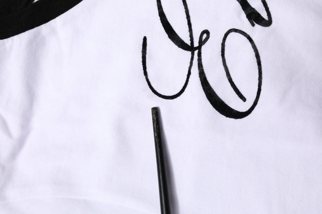 Détail brodé en lettres noires sur tissu blanc du t-shirt col rond en coton dolce & gabbana white eleganza