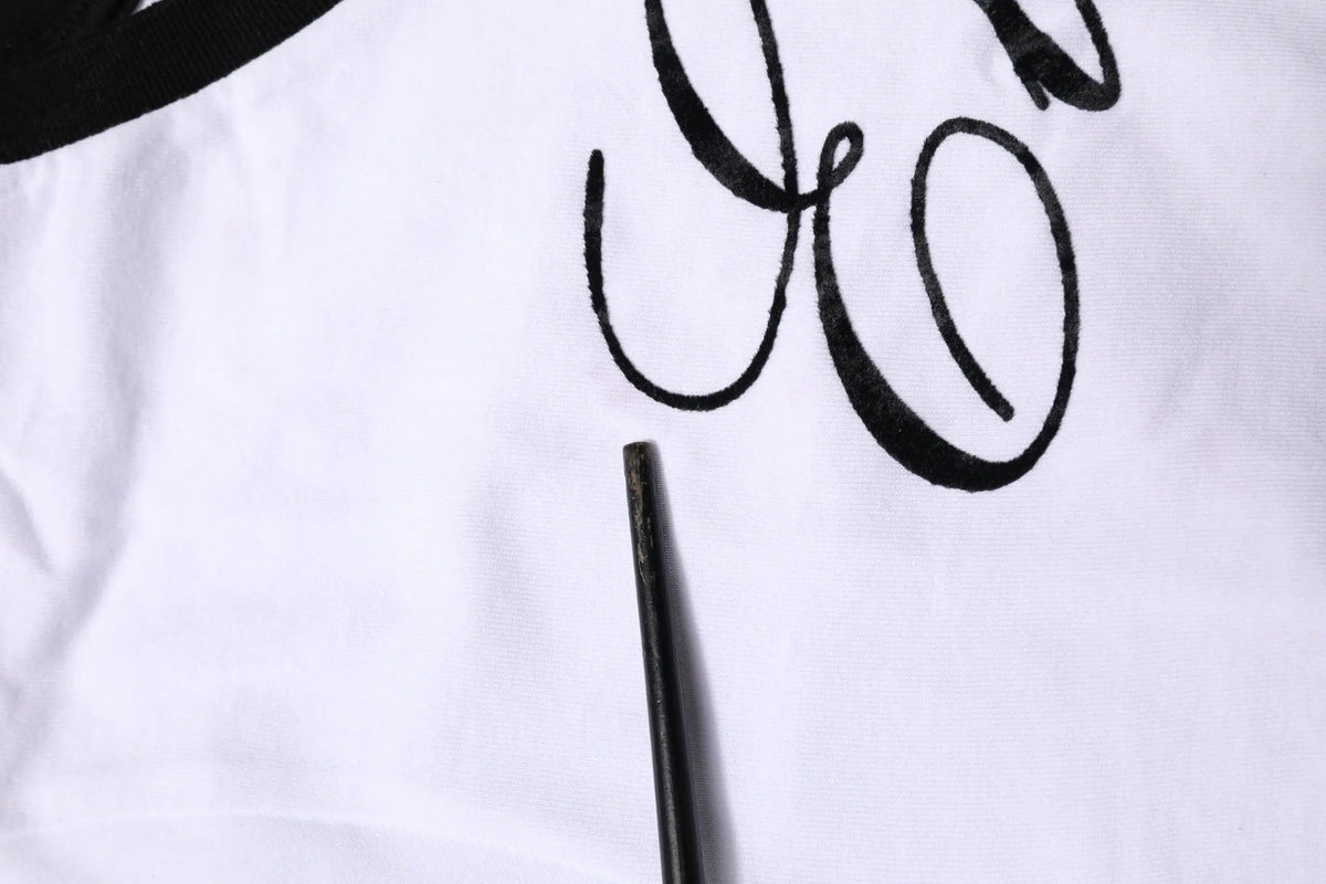 Détail brodé en lettres noires sur tissu blanc du t-shirt col rond en coton dolce & gabbana white eleganza