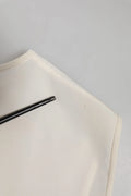 Un stylo noir élégant repose en diagonale sur le tissu blanc orné de cristaux du top fairy embellished de Dolce & Gabbana