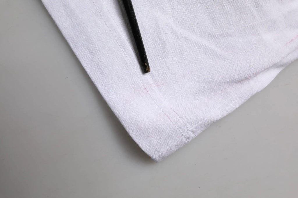 Tissu blanc en coton avec couture soignée sur l’ourlet et plié partiellement sur un crayon noir pour t-shirt dolce & gabbana à manches courtes fleurs