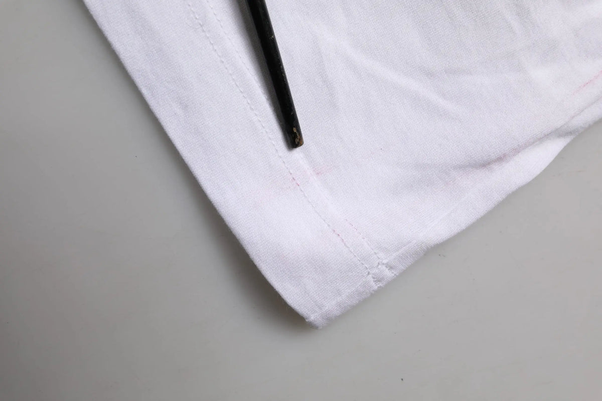 Tissu blanc en coton avec couture soignée sur l’ourlet et plié partiellement sur un crayon noir pour t-shirt dolce & gabbana à manches courtes fleurs