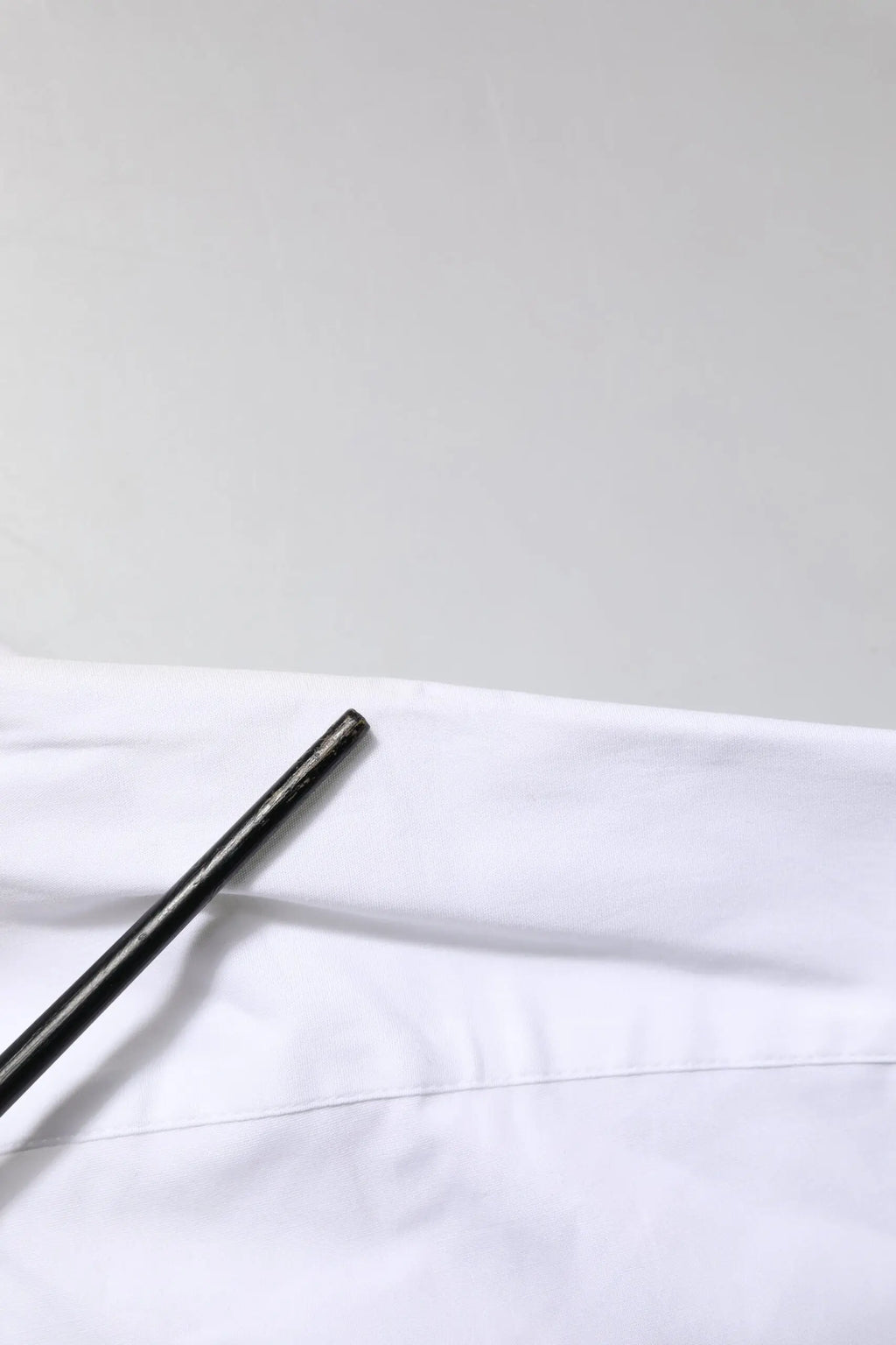 Stylo cylindrique noir posé sur tissu blanc d une chemise dolce & gabbana white gold en coton col à revers