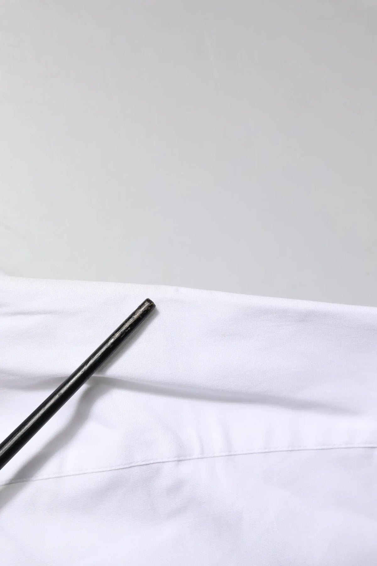 Stylo cylindrique noir posé sur tissu blanc d une chemise dolce & gabbana white gold en coton col à revers