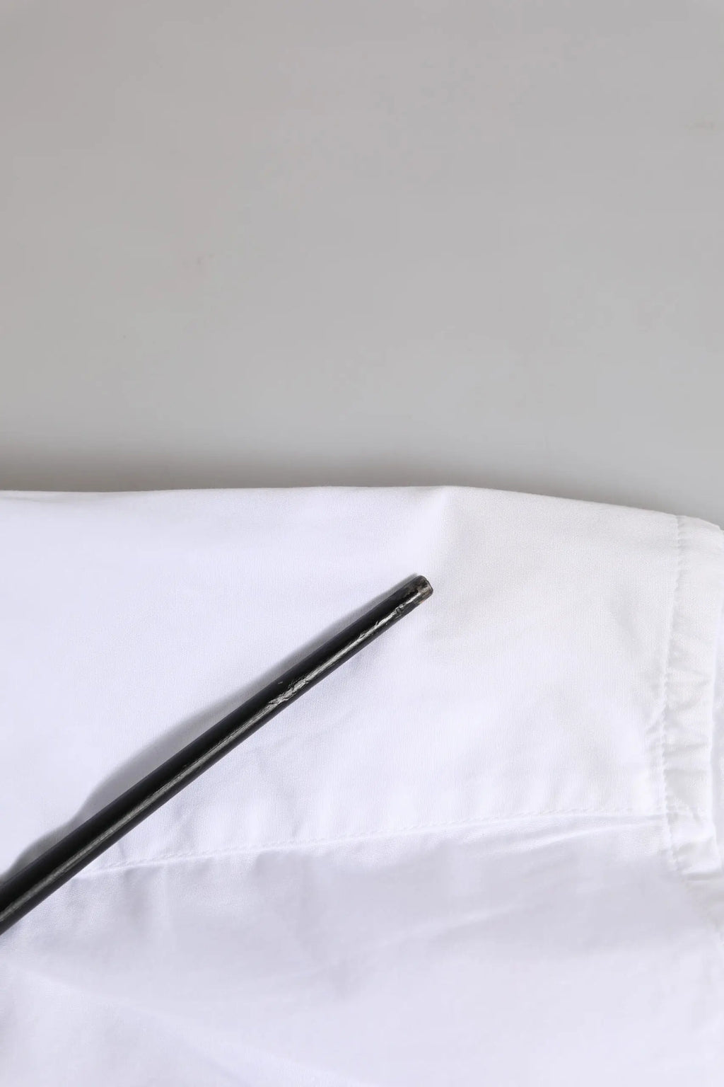 Chopsticks noirs élégants posés sur un tissu blanc net avec une chemise homme formelle à manches longues en coton and or de Dolce & Gabbana