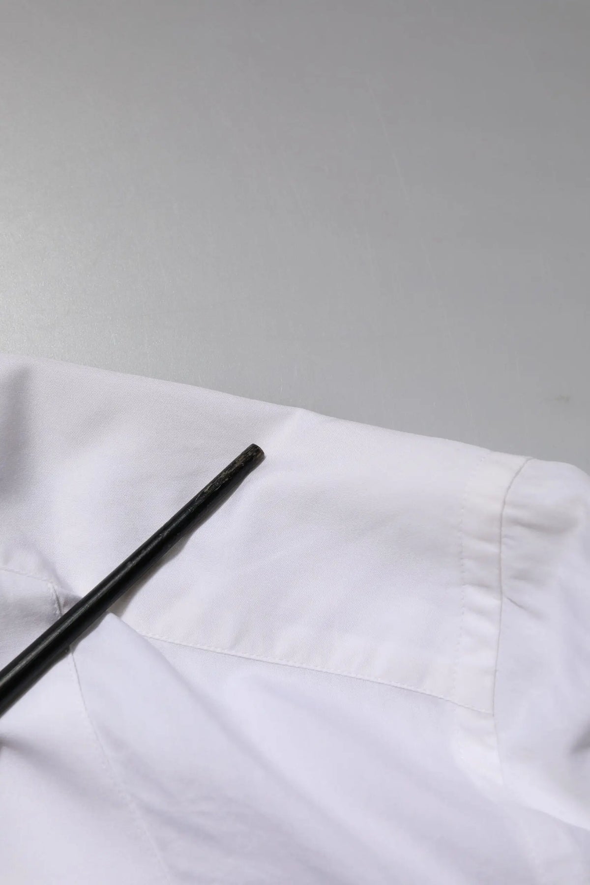Bâtons de chopsticks noirs reposant sur un tissu blanc net proche de la chemise formelle blanche en coton popeline dolce gabbana gold
