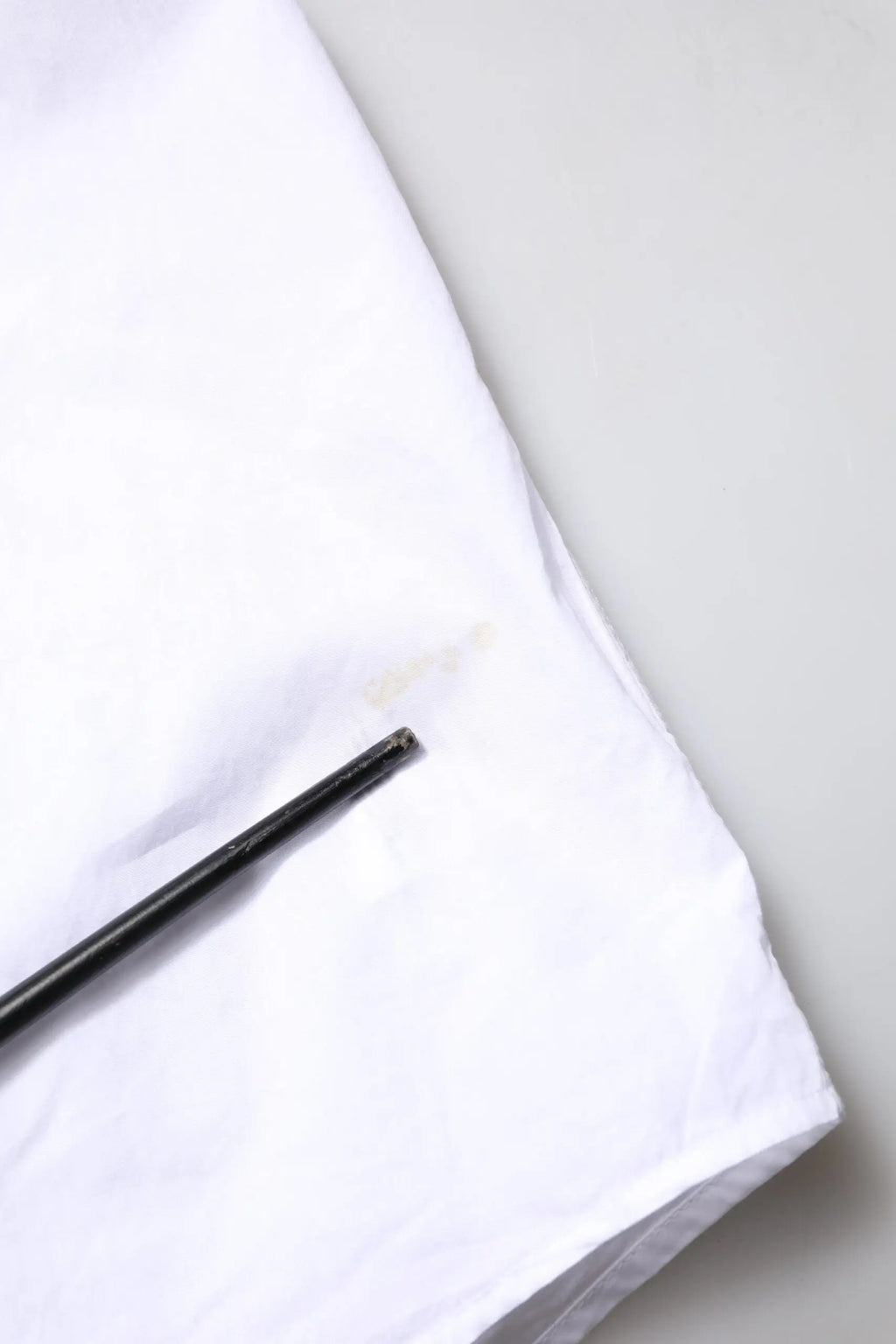 Un repose-baguettes noir élégant posé en diagonale sur une chemise formelle blanche en coton popeline dolce & gabbana