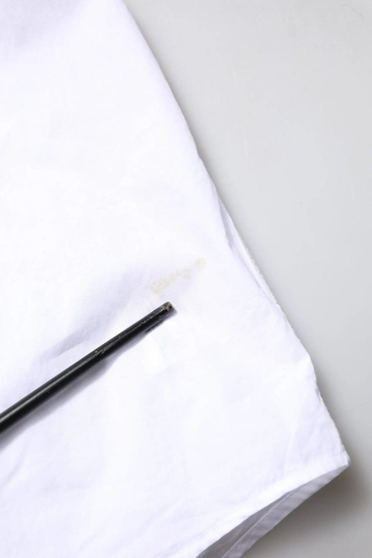 Un repose-baguettes noir élégant posé en diagonale sur une chemise formelle blanche en coton popeline dolce & gabbana