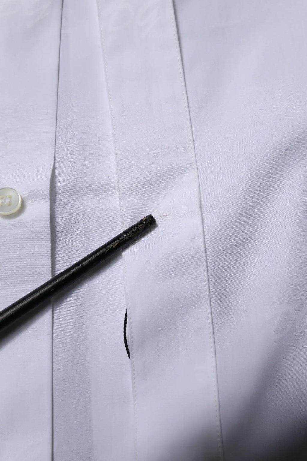 Crayon noir posé sur le tissu blanc en or de la chemise formelle à manches longues dolce & gabbana