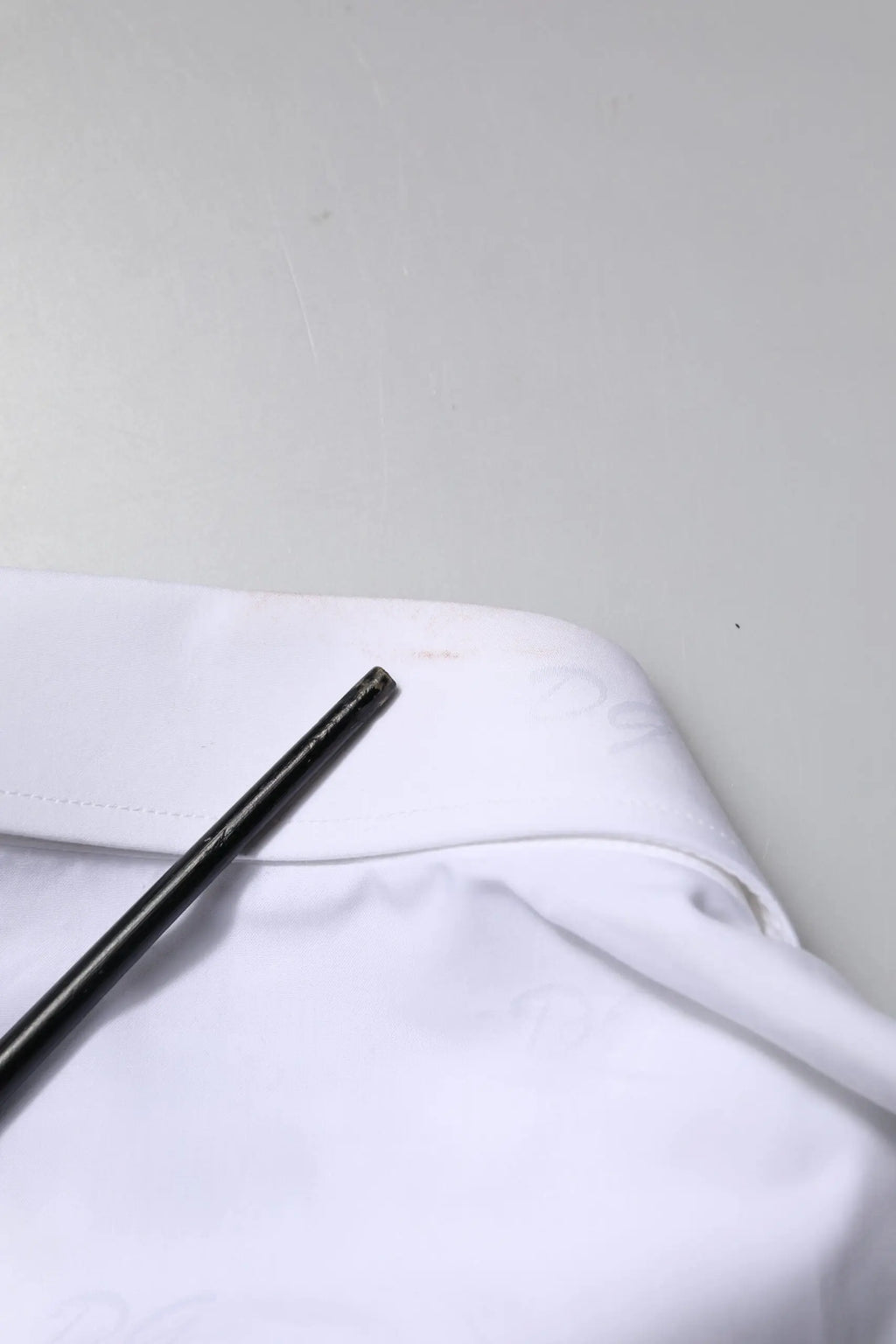 Stylo cylindrique noir posé sur tissu blanc avec chemise formelle blanche en or blanc dolce & gabbana manches longues