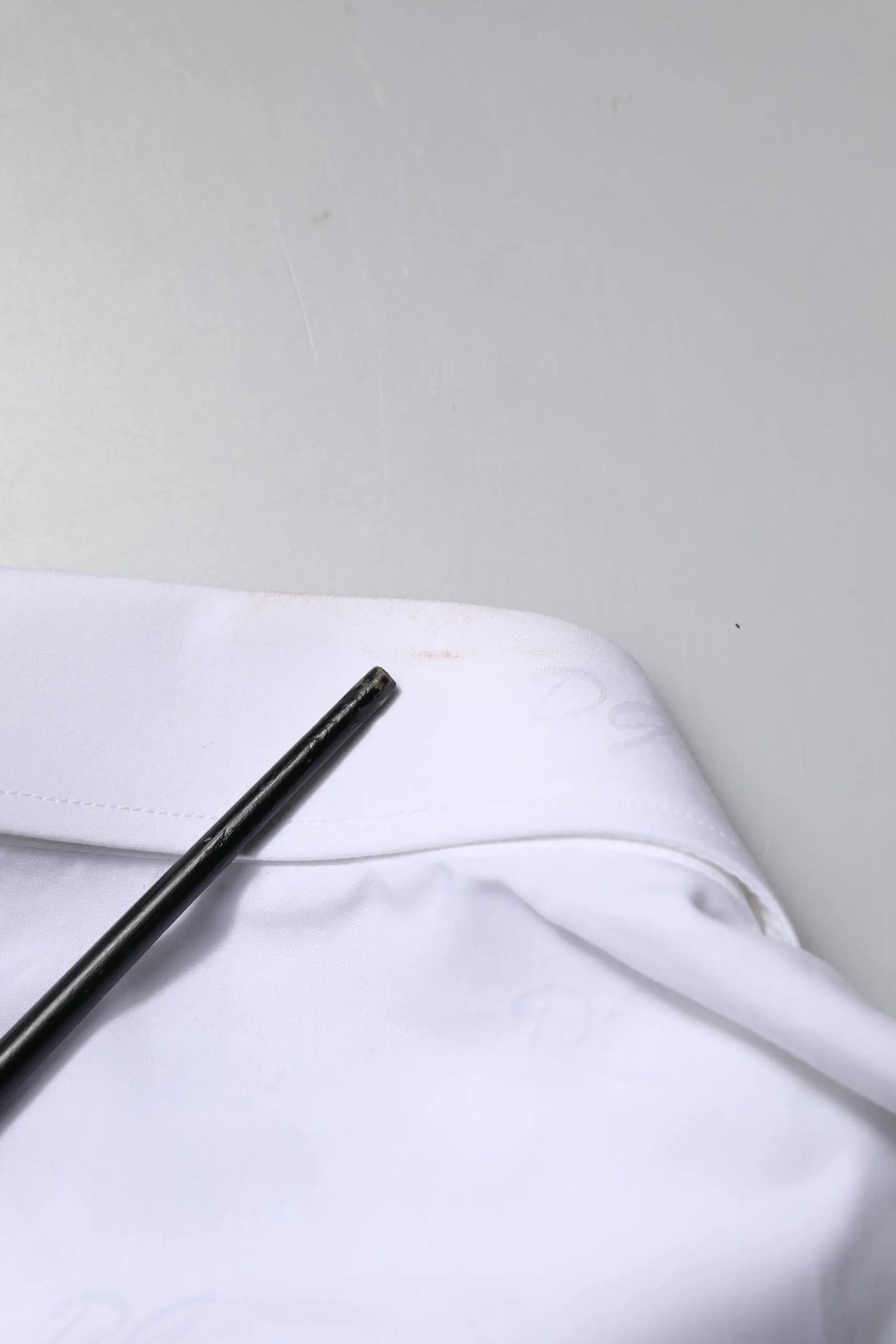 Stylo cylindrique noir posé sur tissu blanc avec chemise formelle blanche en or blanc dolce & gabbana manches longues
