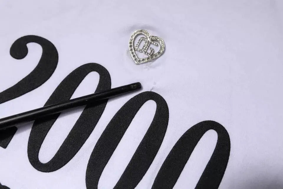 Pin argent en forme de cœur orné de strass et logo dg entrelacé sur t-shirt coton blanc dolce gabbana