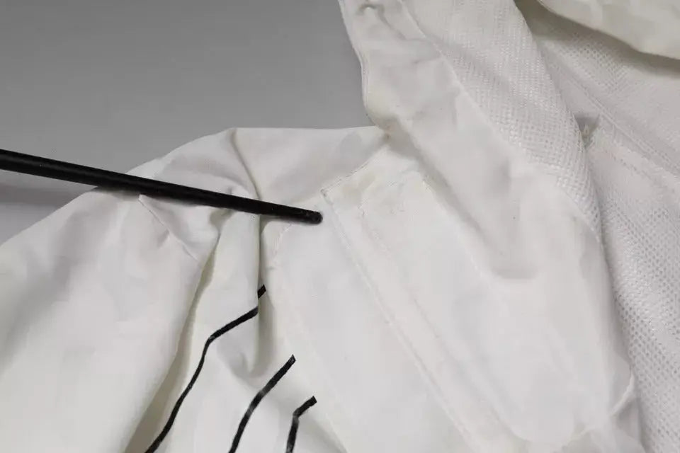 Objet cylindrique noir posé sur tissu blanc avec couture noire du parka trench coat en polyester dolce & gabbana