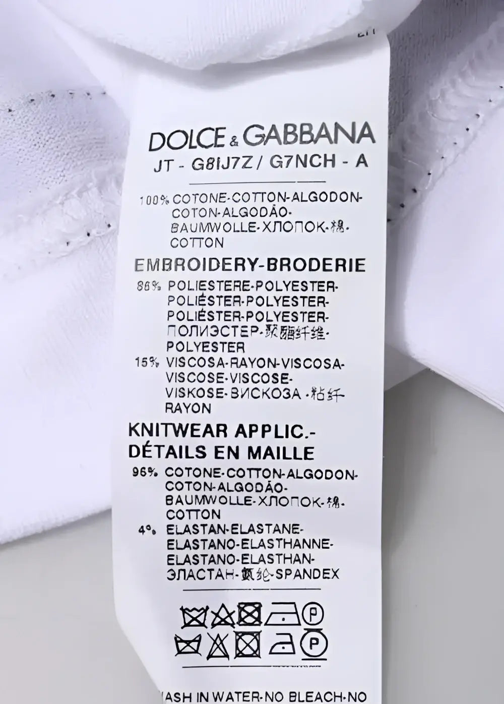 Étiquette de soin blanche dolce gabbana à l’arrière avec composition multilingue tissu et instructions lavage pour t-shirt blanc en jersey manches courtes col rond