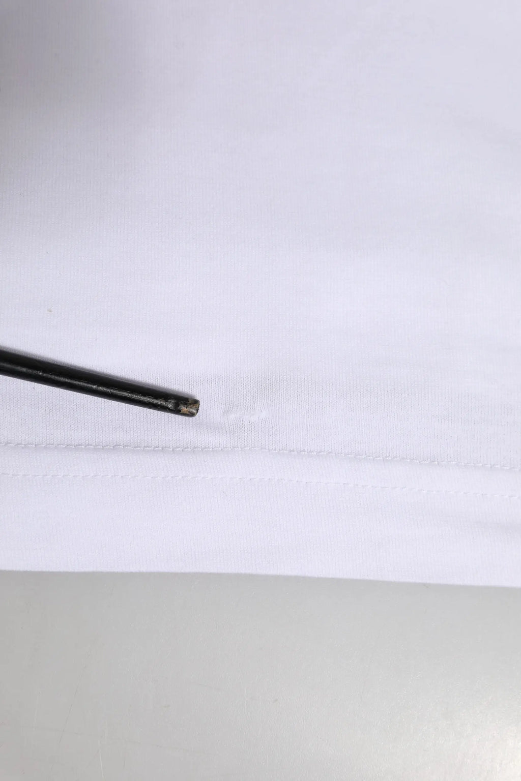 Stylos noir posé sur le bord en tissu blanc d’un t-shirt dolce & gabbana à manches courtes avec logo blanc col rond