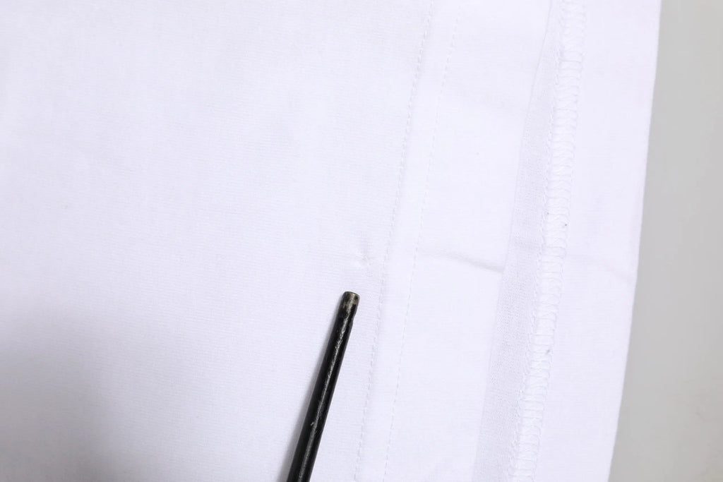 Pointe de crayon noir appuyée contre une couture de tissu blanc sur t shirt dolce gabbana blanc logo col rond manches courtes