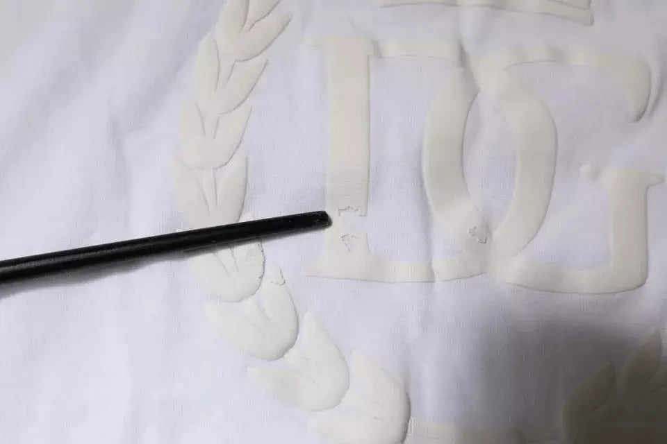 Crayon noir cylindrique reposant sur tissu blanc embossé du logo dolce & gabbana sur t-shirt coton blanc col rond