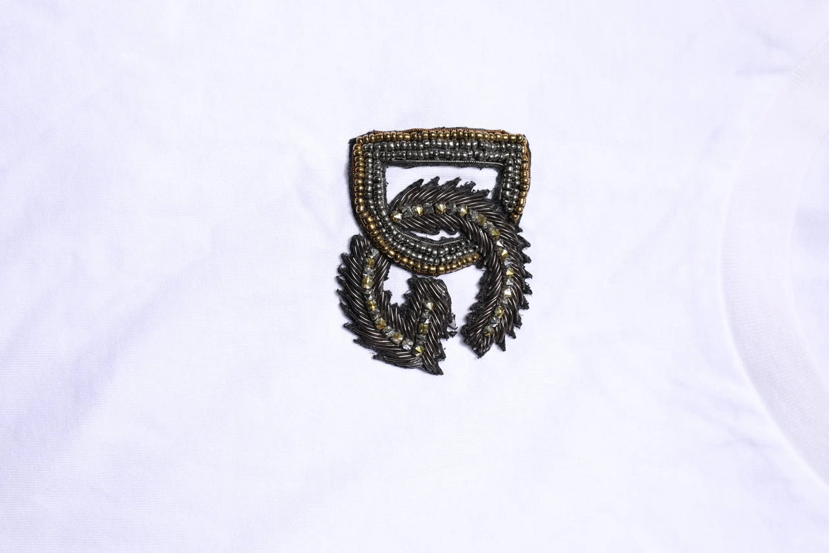 Broche noire et dorée à perles avec bouclier orné et design plumé torsadé sur t-shirt dolce et gabbana blanc avec broderie logo