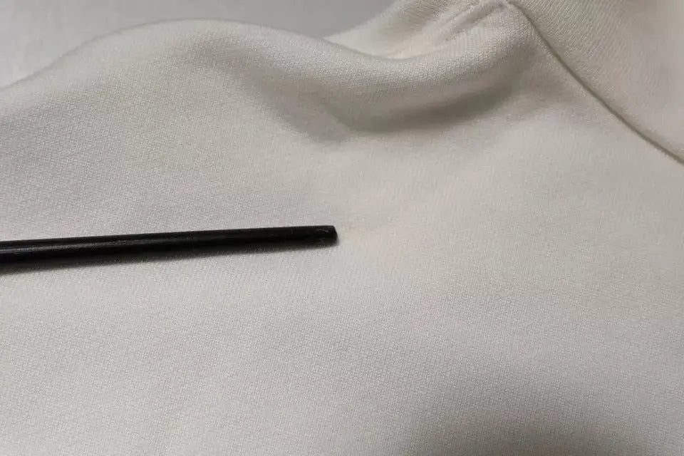 Un repose-baguettes noir élégant sur une surface en tissu blanc cassé doux avec un sweat à capuche dolce gabbana blanc logo homme