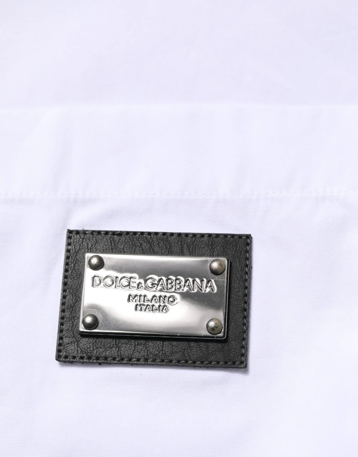 Patch en cuir noir avec plaque métallique argentée dolce & gabbana milano italia sur chemise formelle blanche à col