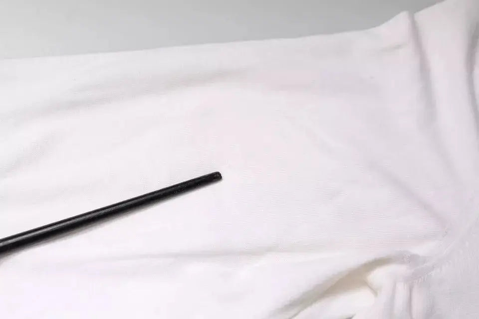 Black cylindrical straw rest on white fabric with dolce & gabbana white long sleeve turtleneck men pullover sweater