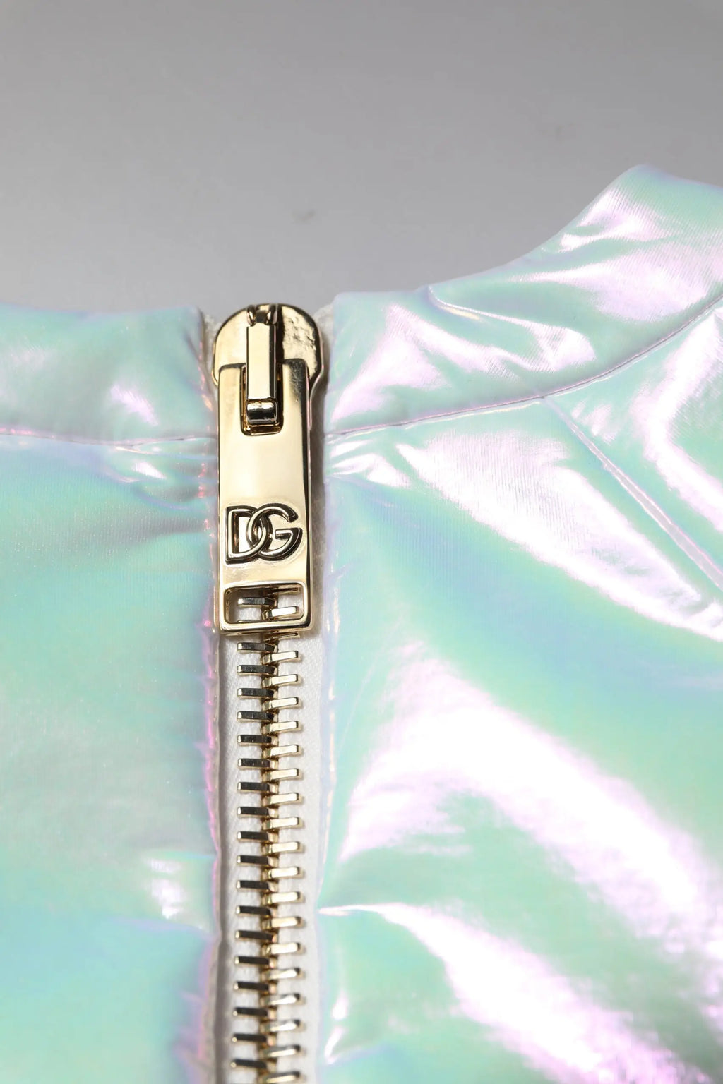 Fermeture éclair dorée d&g sur veste puff irisée verte et bleue accompagnant robe fourreau blanche dolce gabbana manches longues