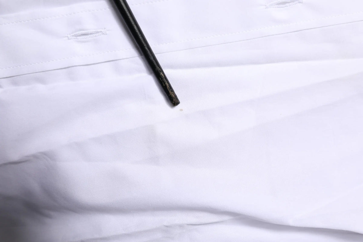 Un crayon noir mince posé en diagonale sur un tissu blanc net du chemisier formel dolce & gabbana white martini manches longues