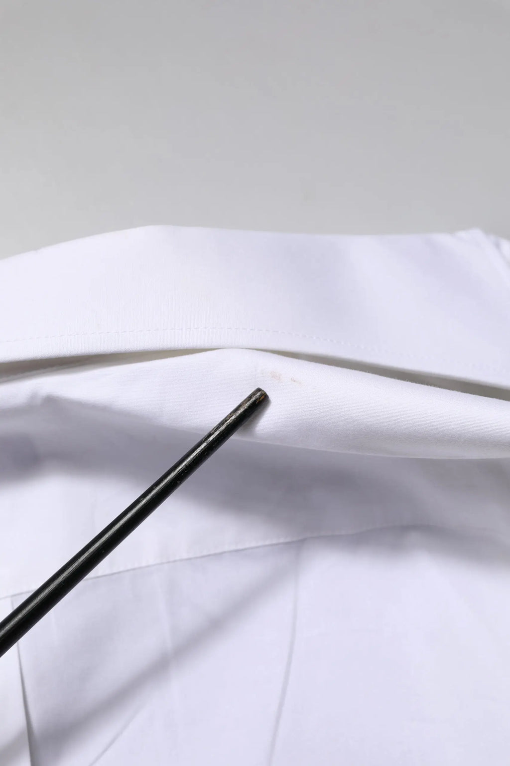 Paire de baguettes noires posées sur une surface en tissu blanc avec chemise formelle blanche martini à manches longues dolce & gabbana