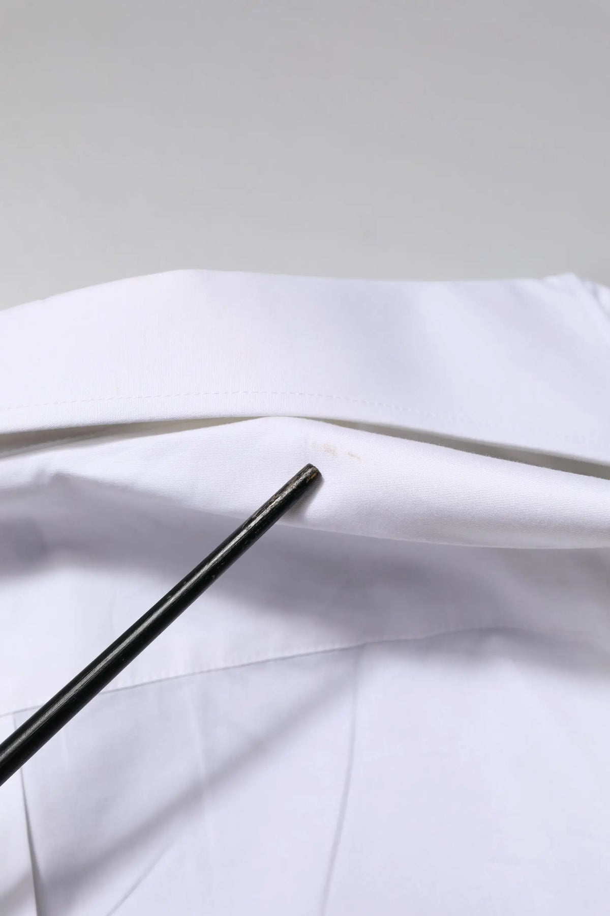 Paire de baguettes noires posées sur une surface en tissu blanc avec chemise formelle blanche martini à manches longues dolce & gabbana