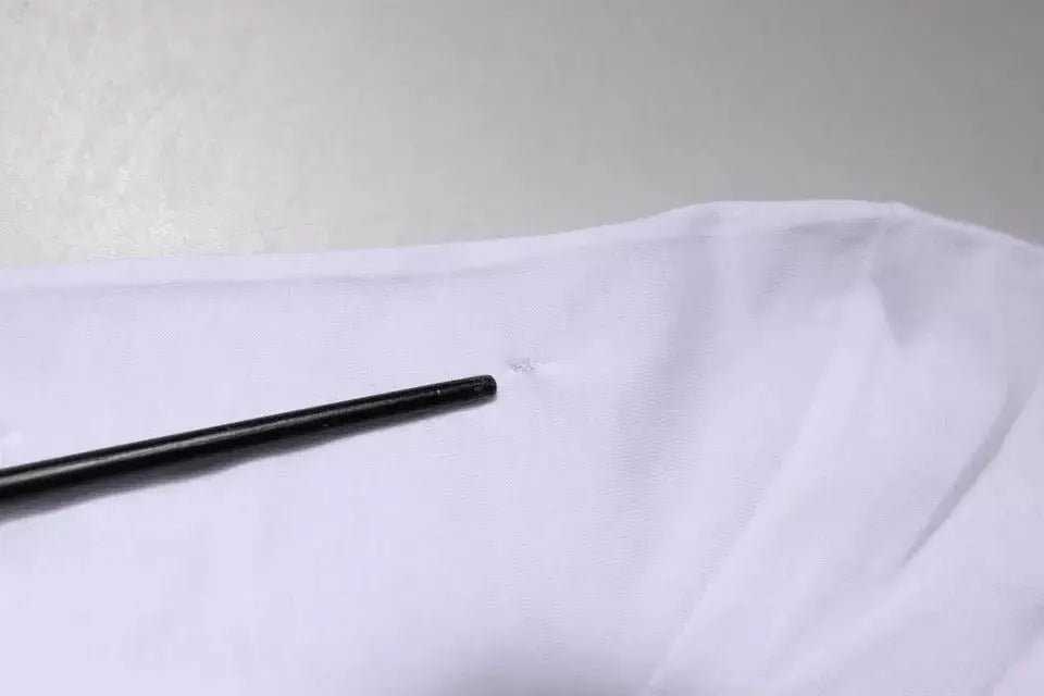 Un objet cylindrique noir élégant posé sur un tissu blanc doux avec un t-shirt dolce & gabbana panda king cotton blanc col rond