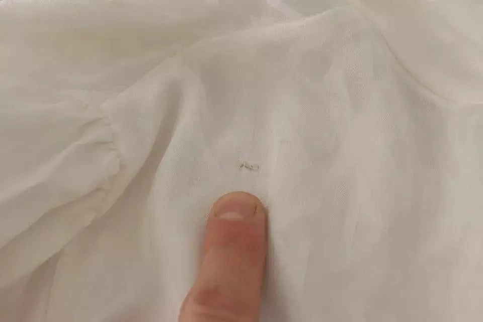 Petit morceau de peluche sombre sur blouse dolce & gabbana blanche en soie à col ascot à motif