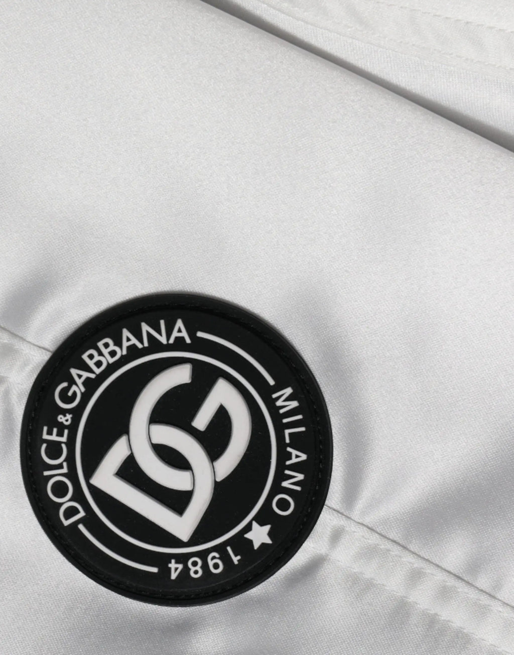 Patch circulaire blanche avec bord noir et logo dolce & gabbana milano 1984 sur blouson bomber blanc en polyester à fermeture éclair complète