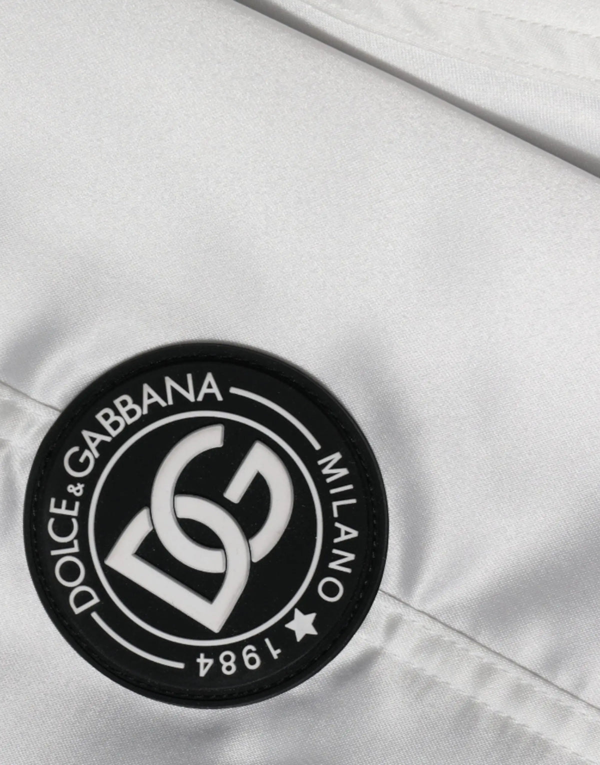 Patch circulaire blanche avec bord noir et logo dolce & gabbana milano 1984 sur blouson bomber blanc en polyester à fermeture éclair complète