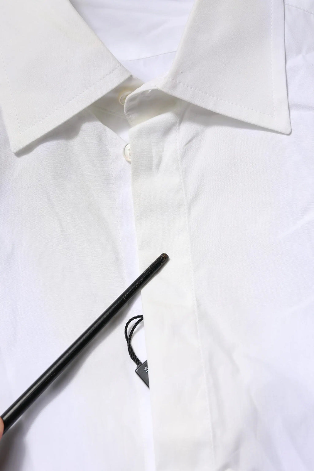 Un stylo noir mat avec une étiquette triangulaire sur une chemise formelle blanche en coton popeline dolce & gabbana