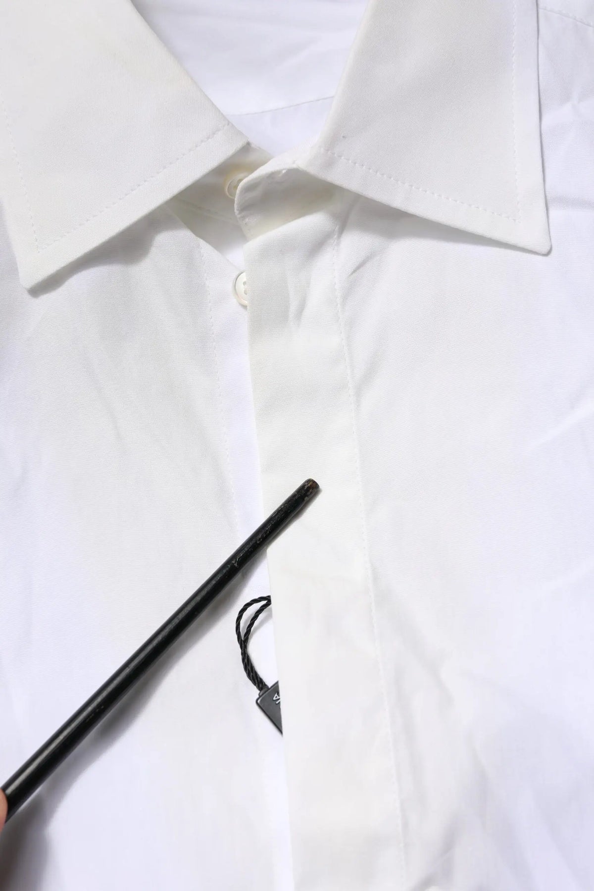 Un stylo noir mat avec une étiquette triangulaire sur une chemise formelle blanche en coton popeline dolce & gabbana