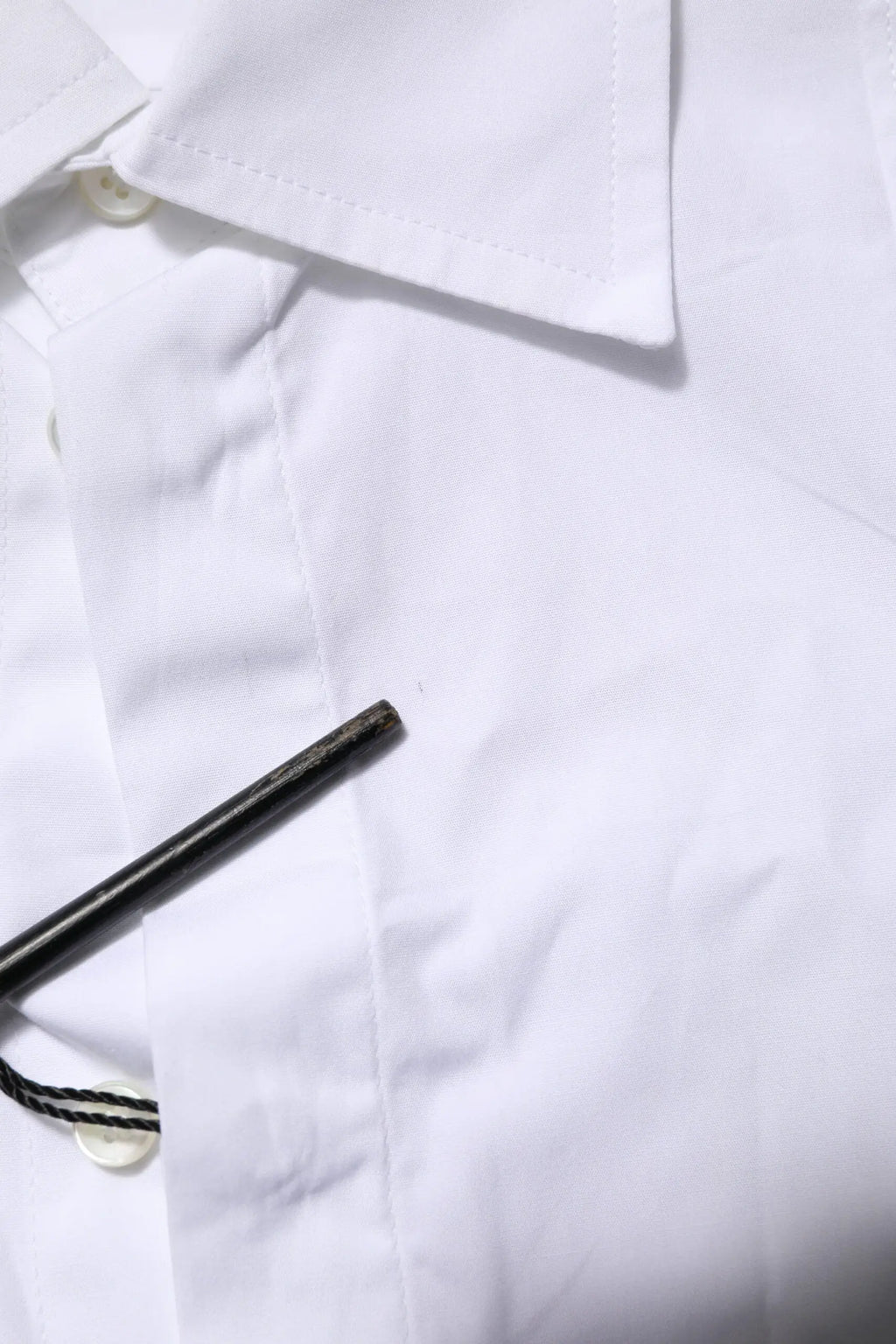 Un stylo noir élégant posé en diagonale sur une chemise blanche en popeline de coton formelle pour homme dolce gabbana