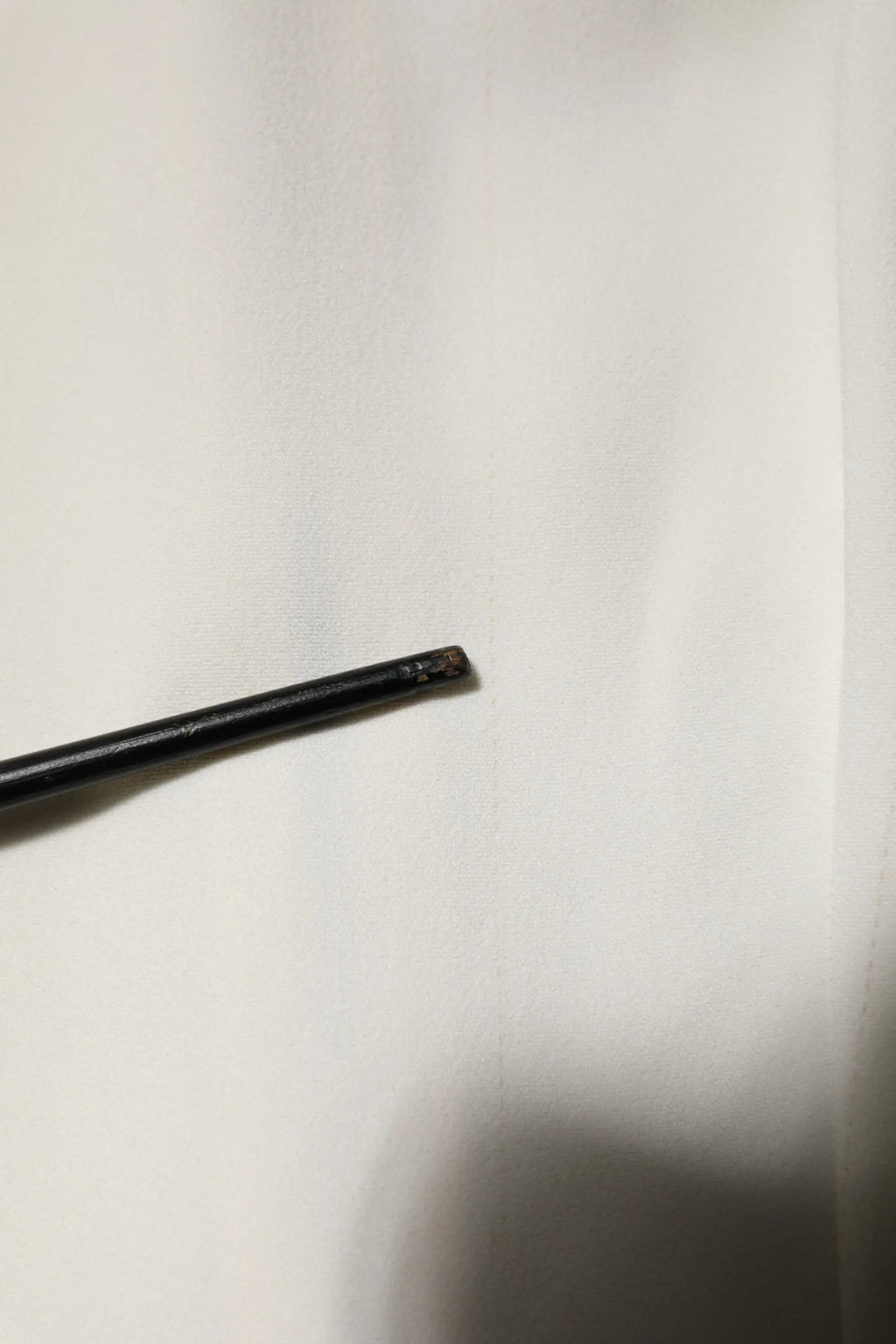 Stylo cylindrique noir à finition mate avec pointe légèrement usée sur blouse blanche dolce gabbana manches courtes col rond