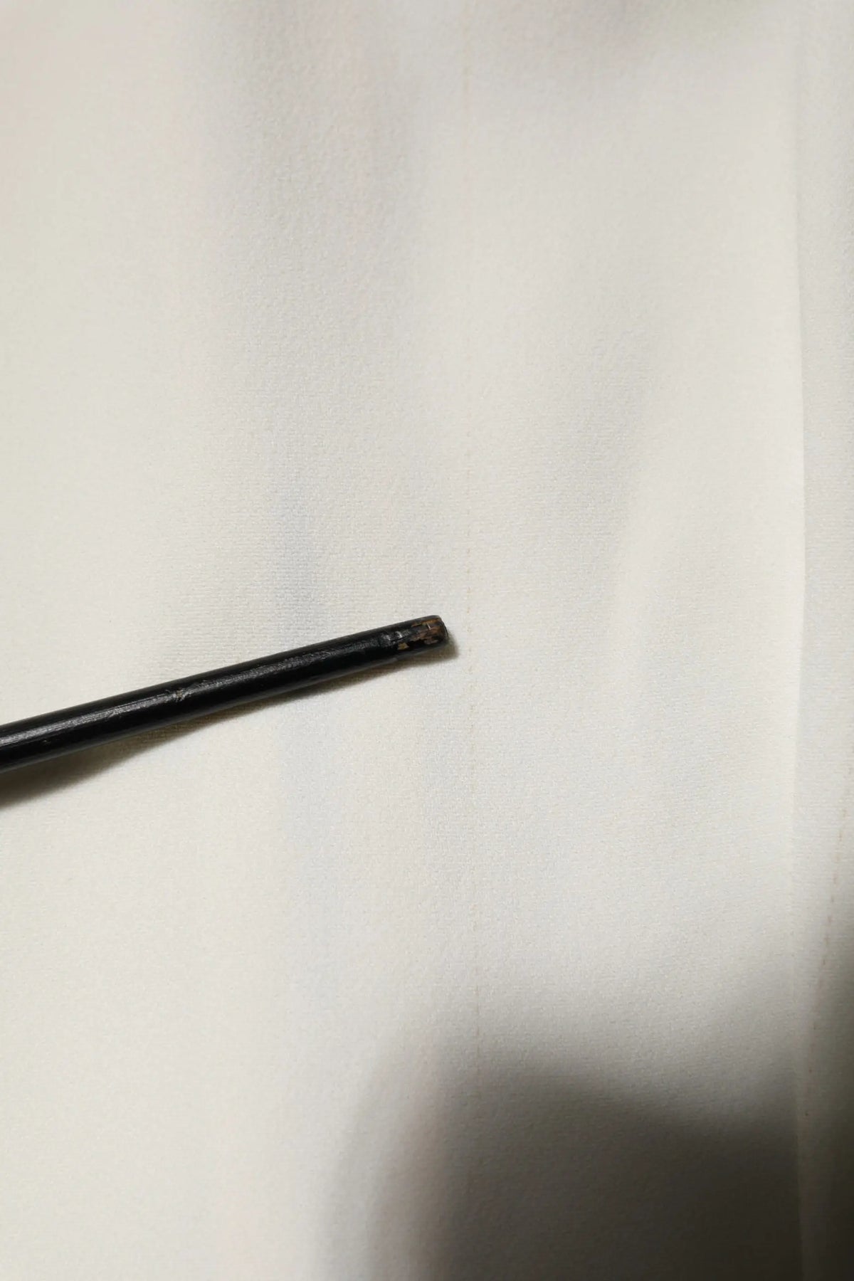 Stylo cylindrique noir à finition mate avec pointe légèrement usée sur blouse blanche dolce gabbana manches courtes col rond