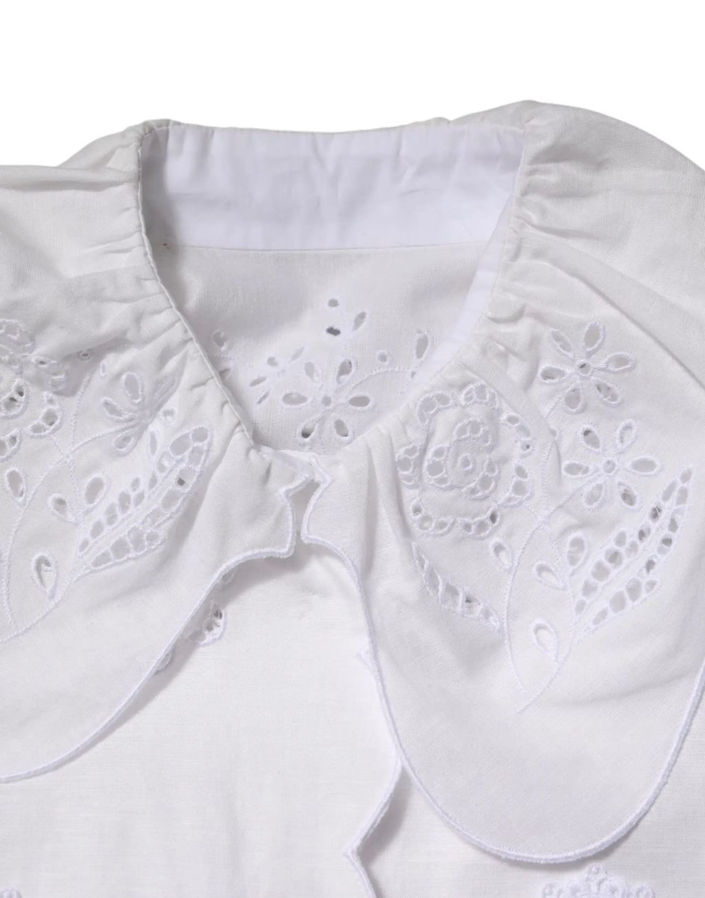Col blanc brodé avec motifs floraux délicats et texture plissée douce sur blouse dolce gabbana en dentelle
