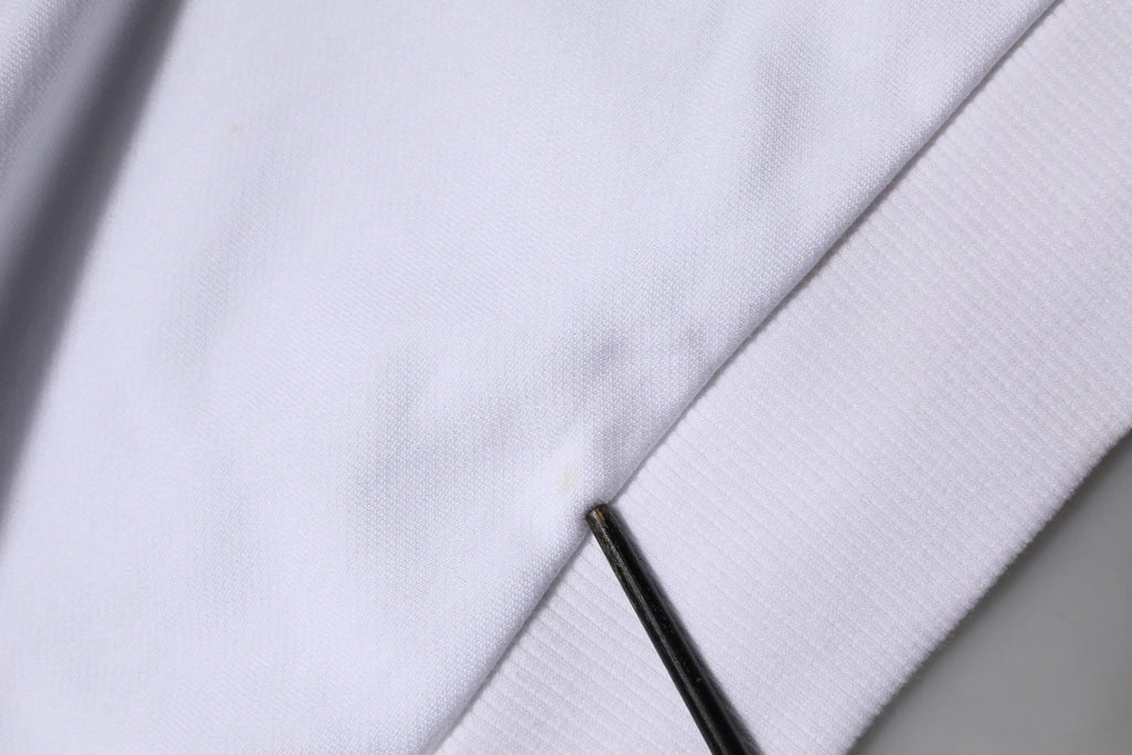 Une aiguille noire élégante posée sur le tissu blanc doux du sweatshirt à capuche dolce & gabbana sacred heart