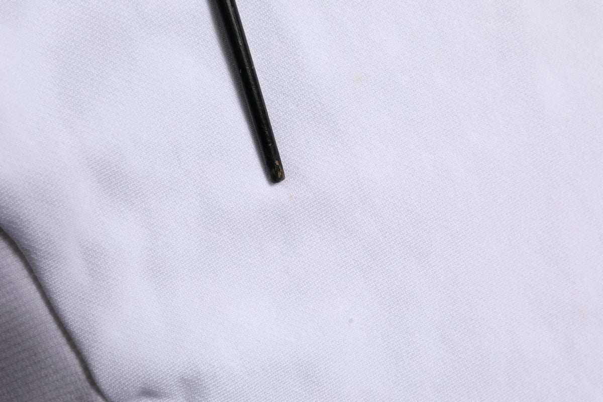 Outil cylindrique noir avec embout légèrement usé posé sur tissu blanc proche du sweat à capuche blanc dolce & gabbana sacred heart