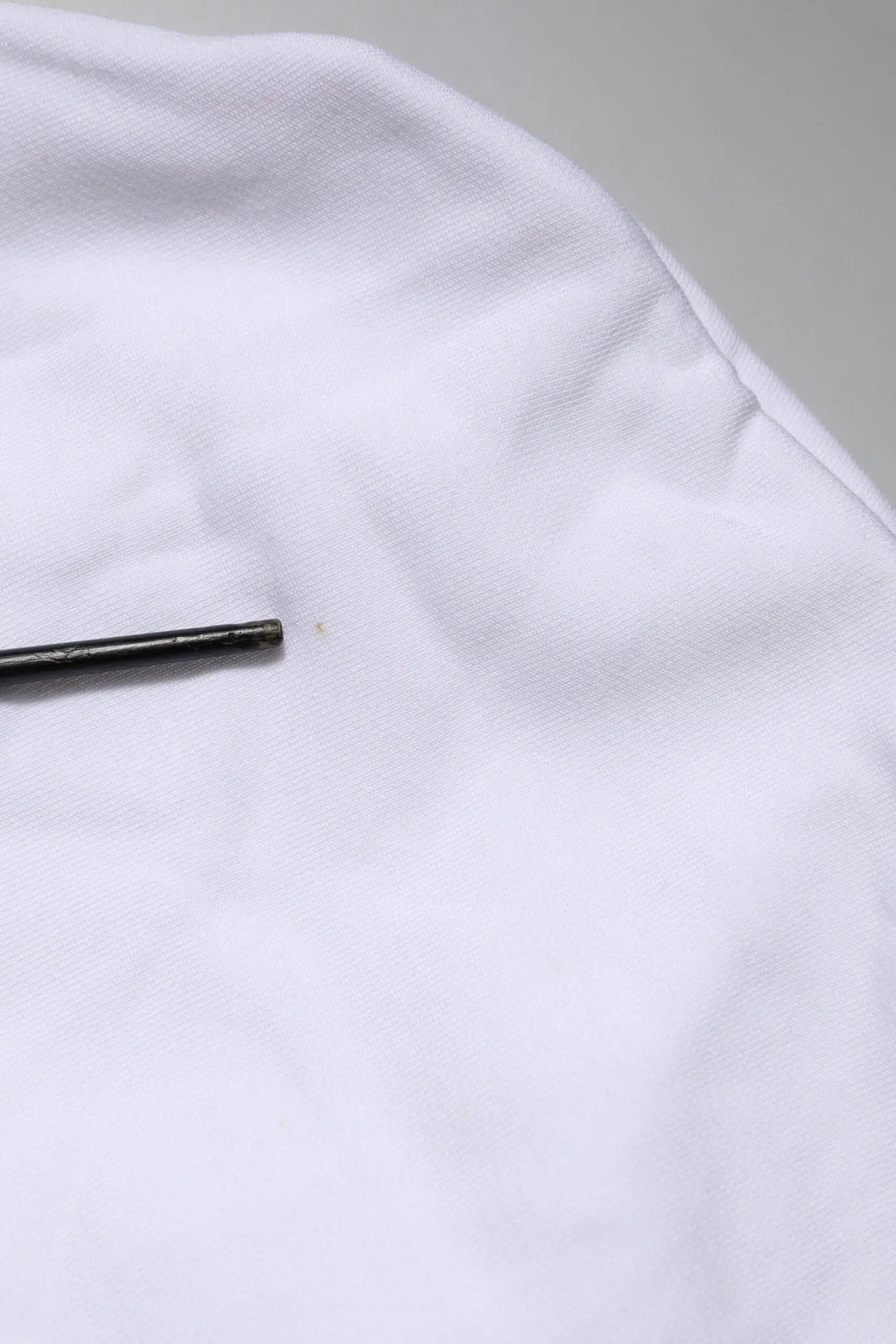 Un objet cylindrique noir élégant posé sur un tissu blanc doux avec le sweat à capuche dolce & gabbana white sacred heart