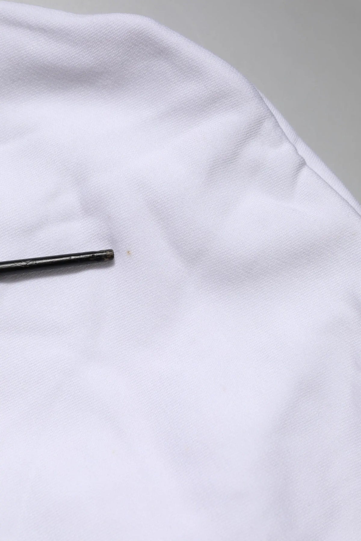 Un objet cylindrique noir élégant posé sur un tissu blanc doux avec le sweat à capuche dolce & gabbana white sacred heart