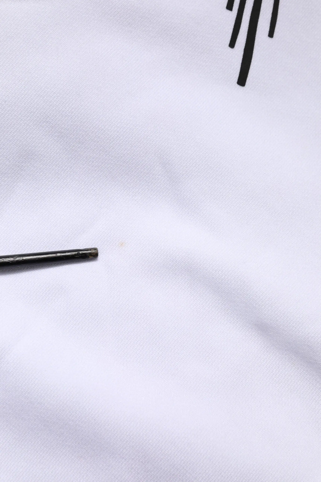 Aiguille métallique noire légèrement usée posée sur tissu blanc du sweat à capuche dolce gabbana white sacred heart
