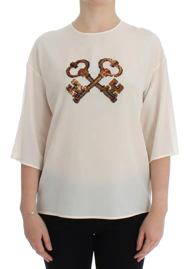 Blouse en soie crème dolce & gabbana avec croix audacieuse de clés en laiton ancien à sequins sur la poitrine