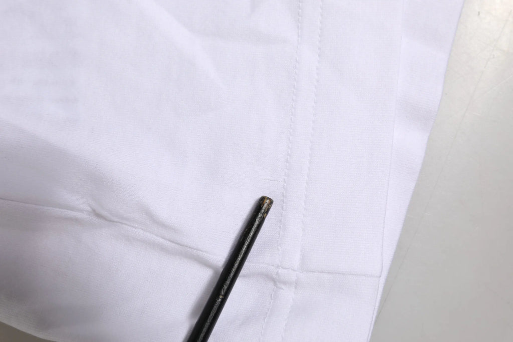 Aiguille noire fine posée sur tissu blanc net du t shirt dolce gabbana blanc manches courtes avec logo dg