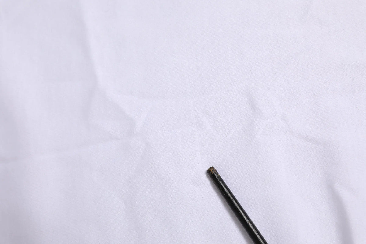 Crayon noir avec pointe légèrement usée posé sur un tissu blanc du t-shirt dolce & gabbana manches courtes blanc avec logo dg