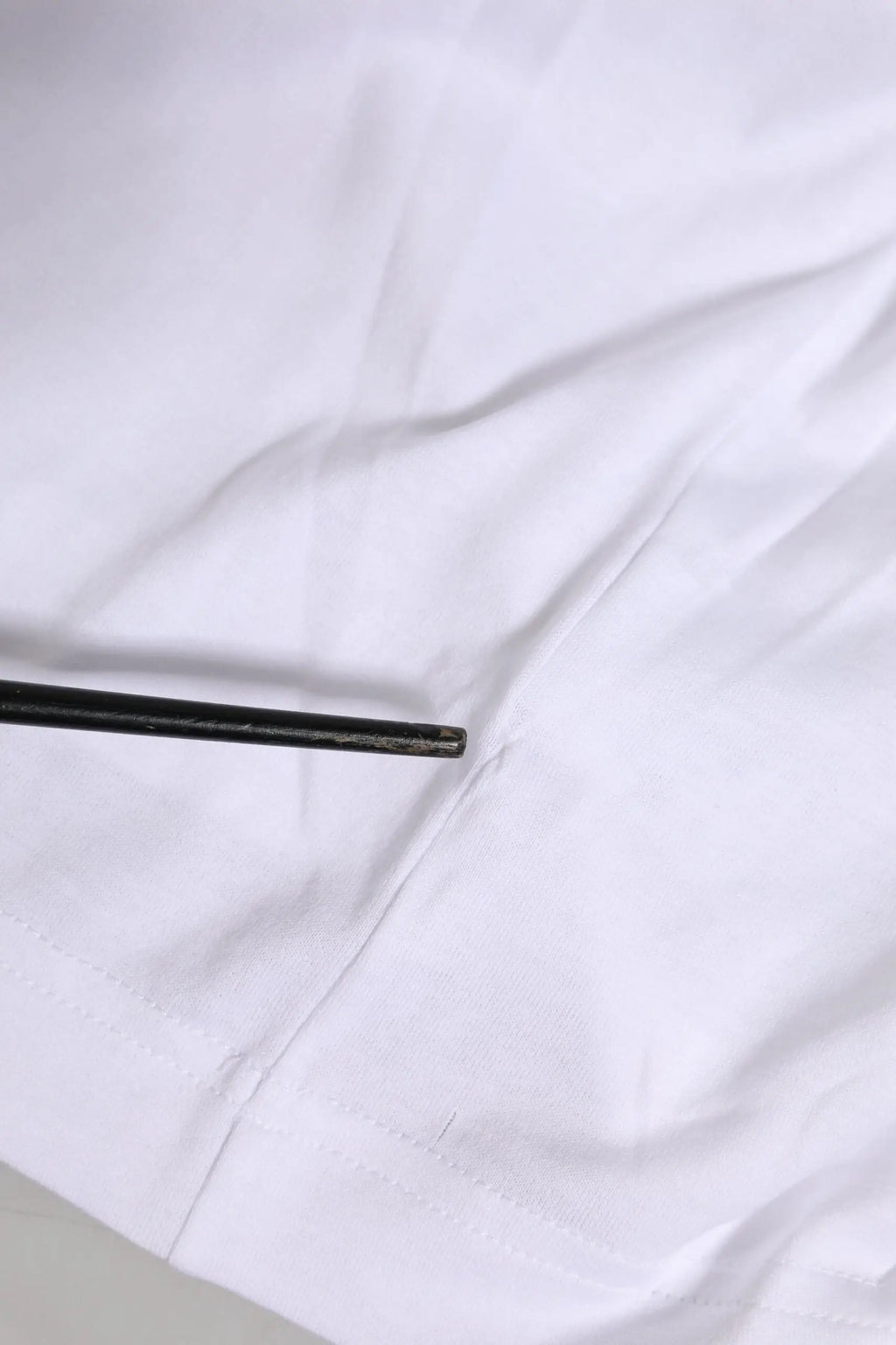 Chopsticks noirs reposant sur un tissu blanc avec un t-shirt dolce & gabbana blanc manches courtes logo dg