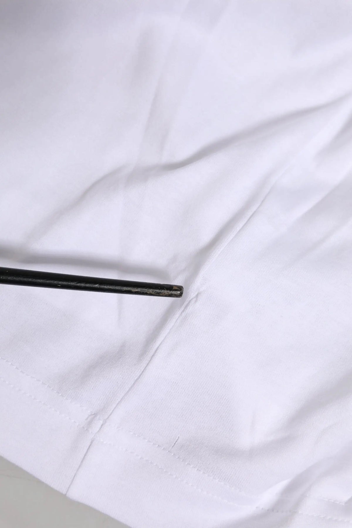 Chopsticks noirs reposant sur un tissu blanc avec un t-shirt dolce & gabbana blanc manches courtes logo dg