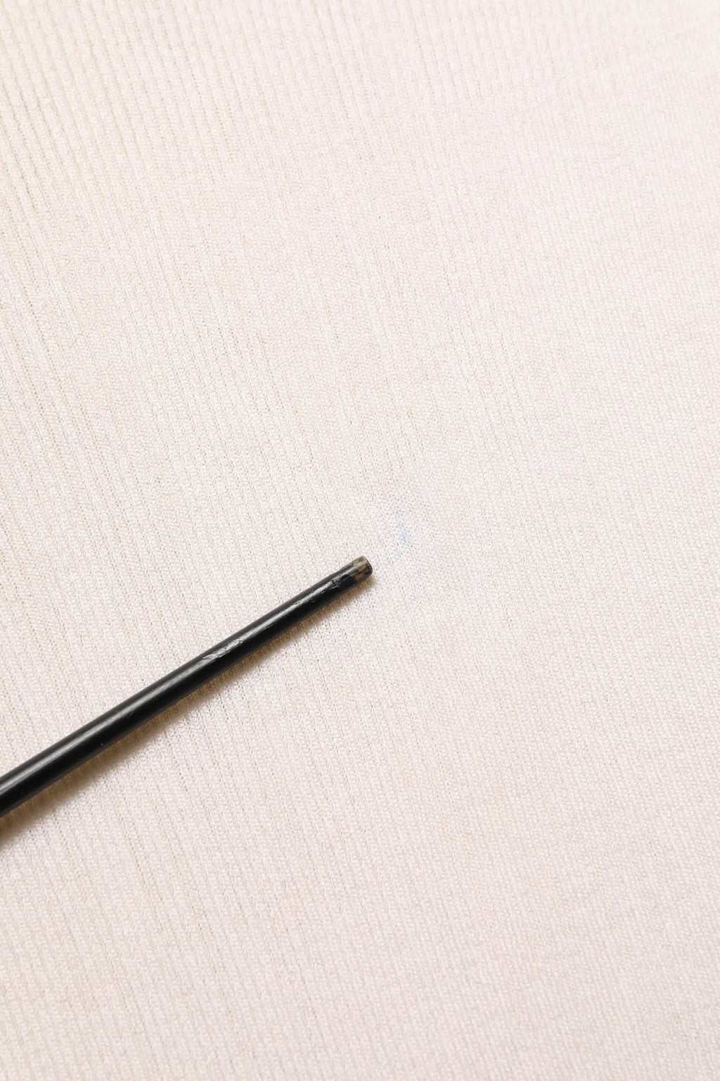 Stylo cylindrique noir mat avec embout gomme à côté d un pull homme dolce & gabbana en soie blanche col rond