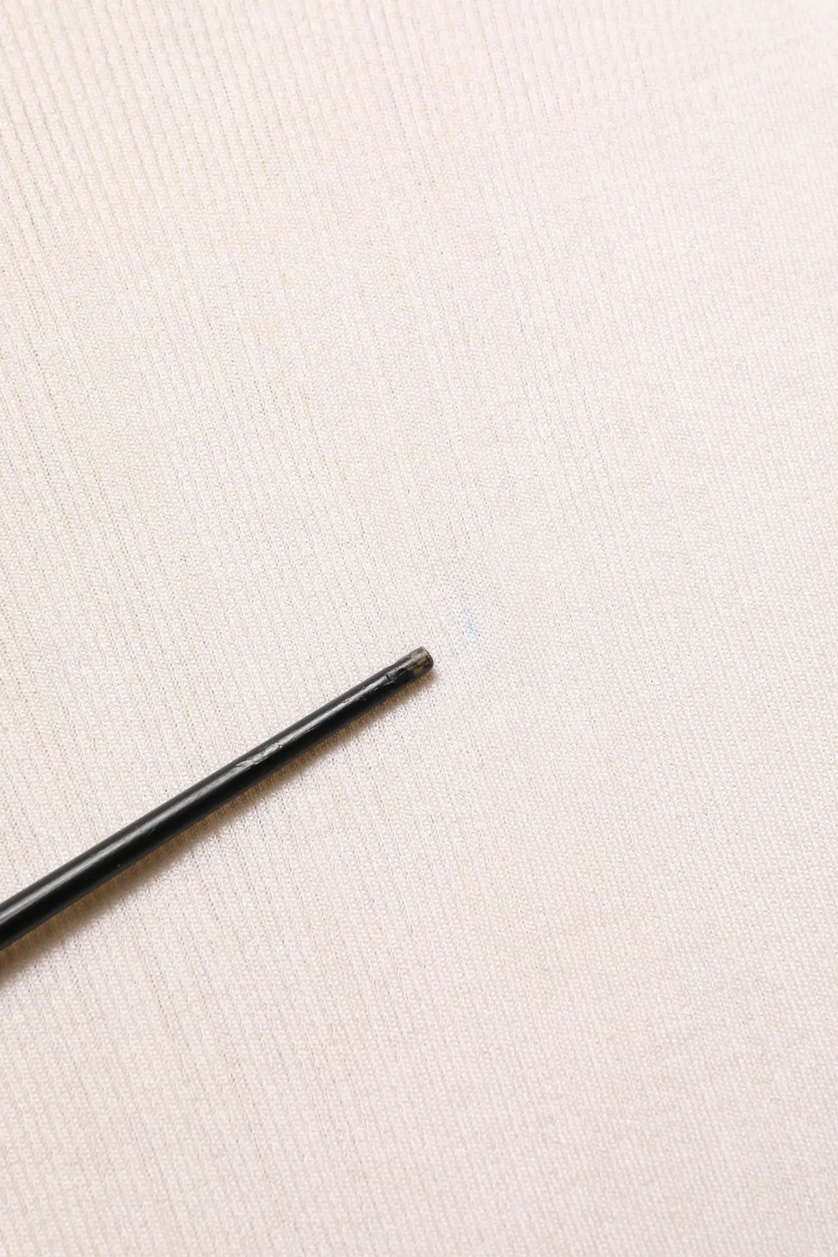 Stylo cylindrique noir mat avec embout gomme à côté d un pull homme dolce & gabbana en soie blanche col rond